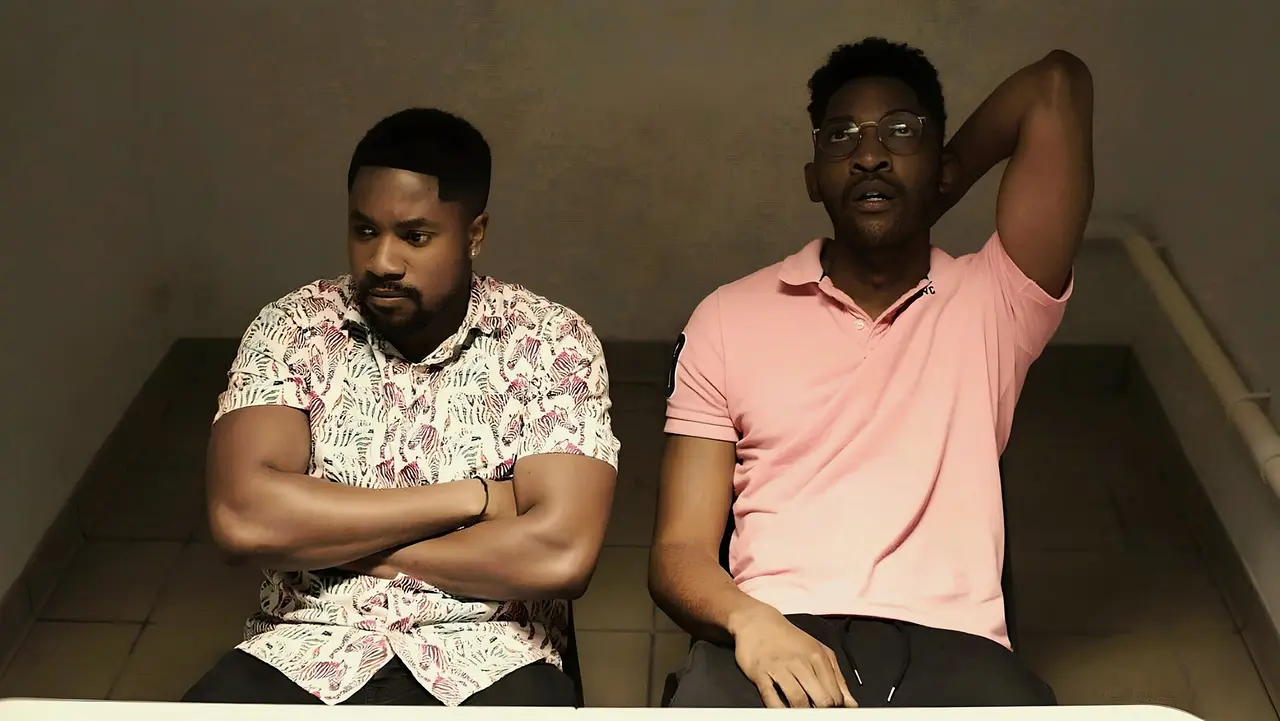 Eniola and Jordan sitting together in a police lock-up
